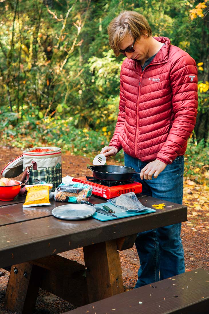 Michael standing at a camping table cooking over a camp stove