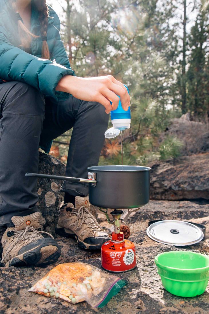 Pouring oil from a blue humangear gotoob+ into a backpacking meal