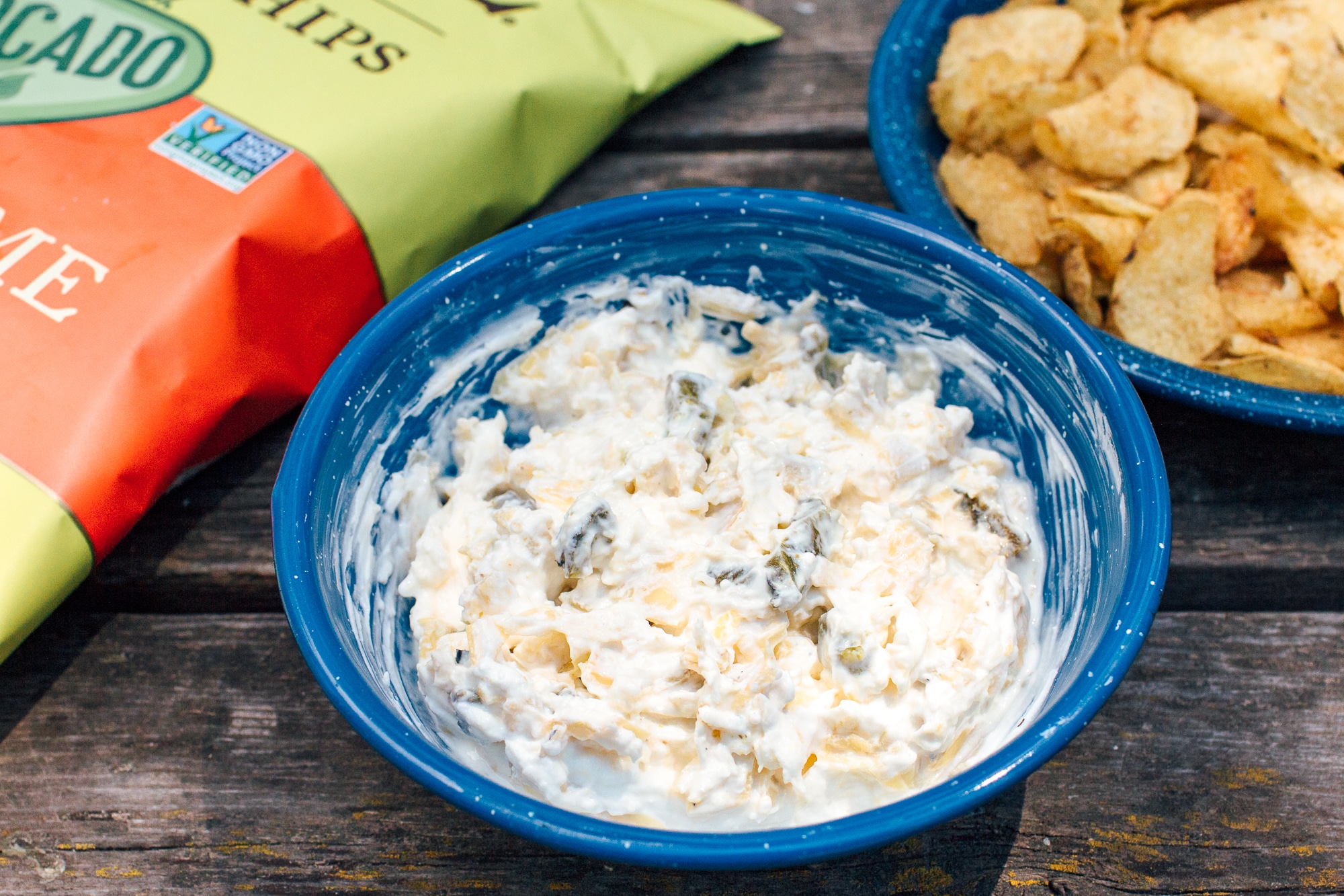 Jalapeno Artichoke dip in a blue enamel bowl on a wooden surface.