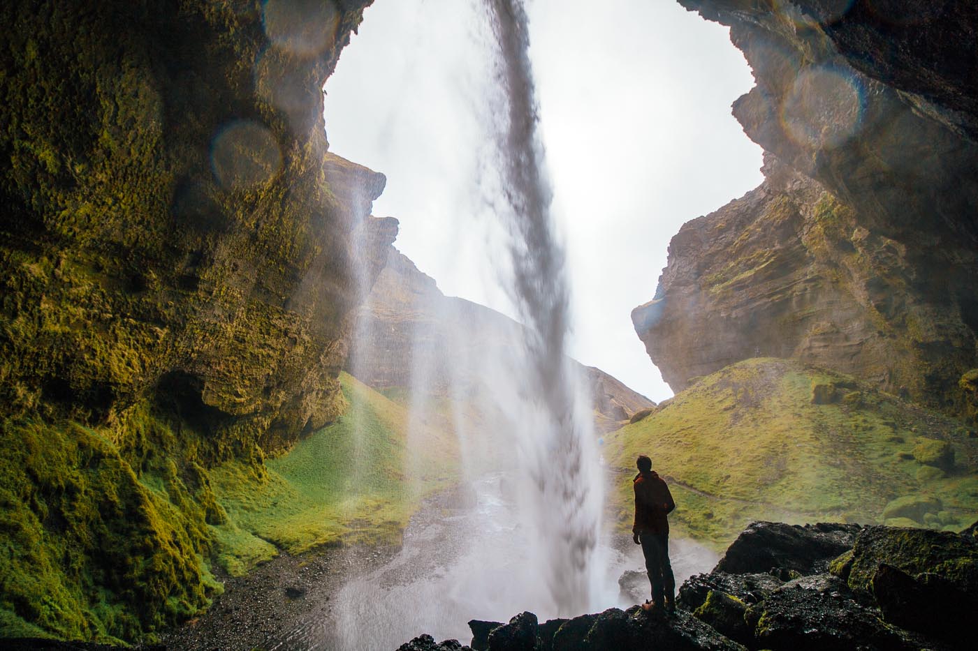 Man standing under the Kvernufoss waterfall