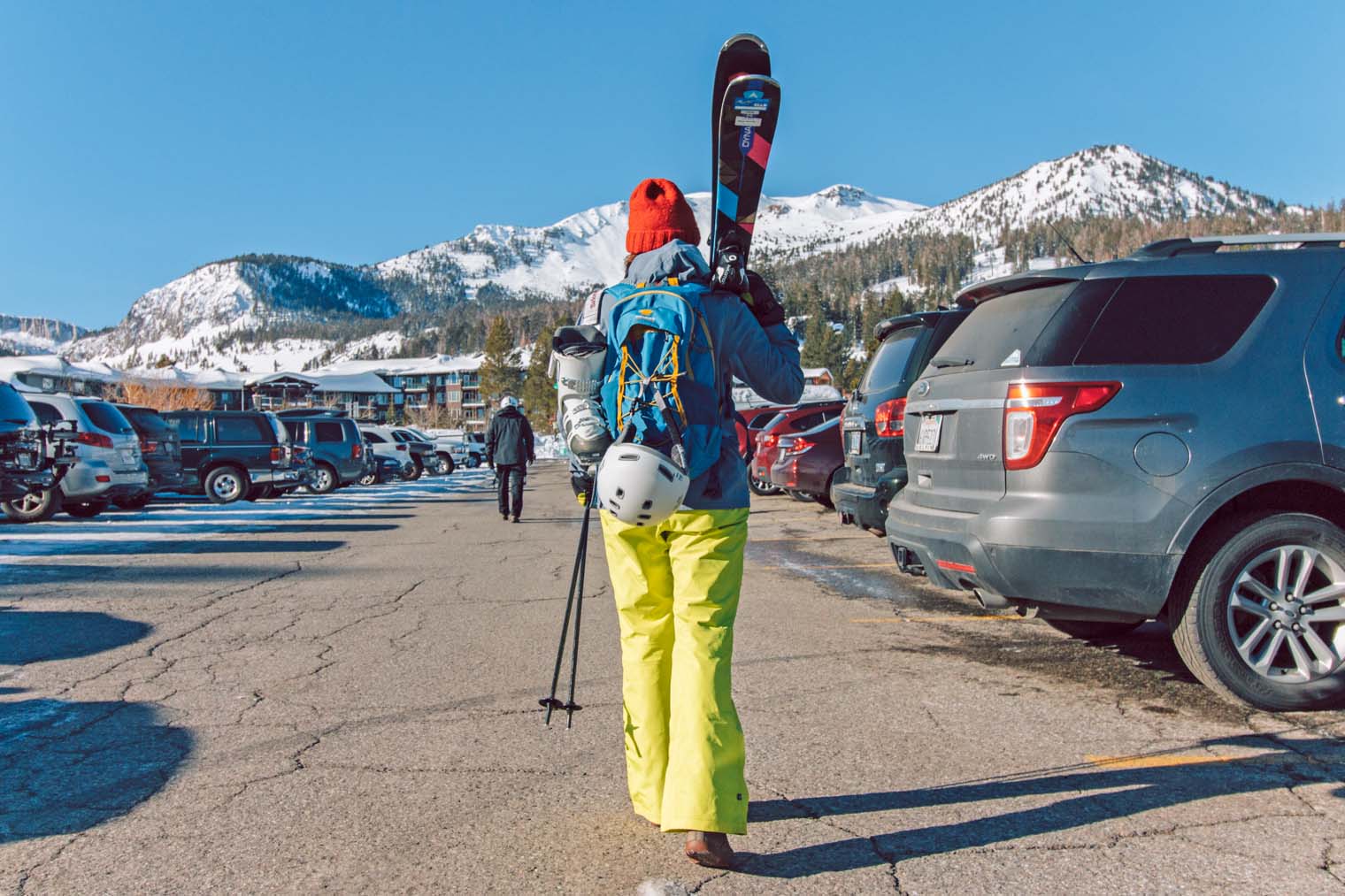 Megan carrying skis in a parking lot