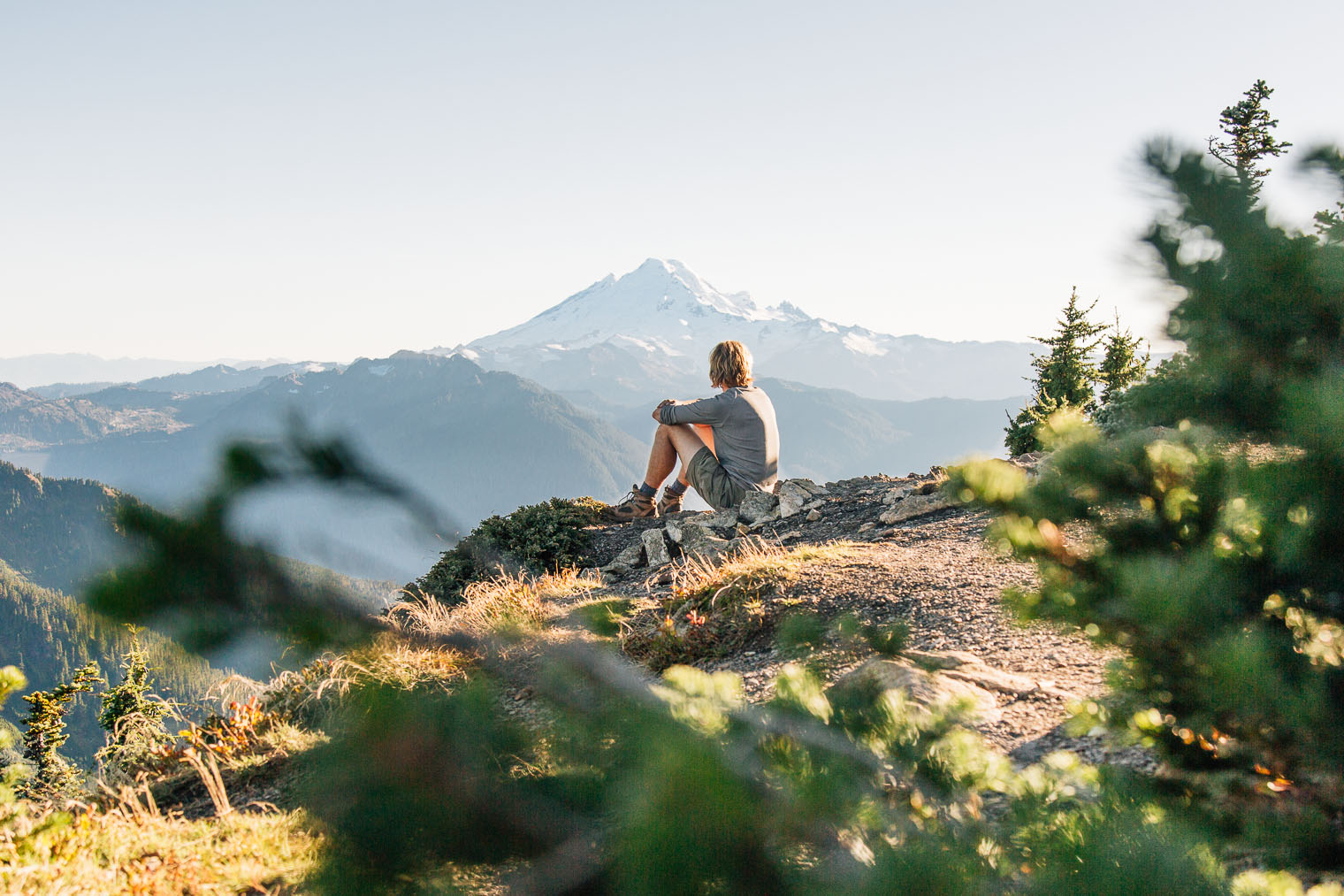 Michael sitting on an outcropping of rocks with a mountain in the distance