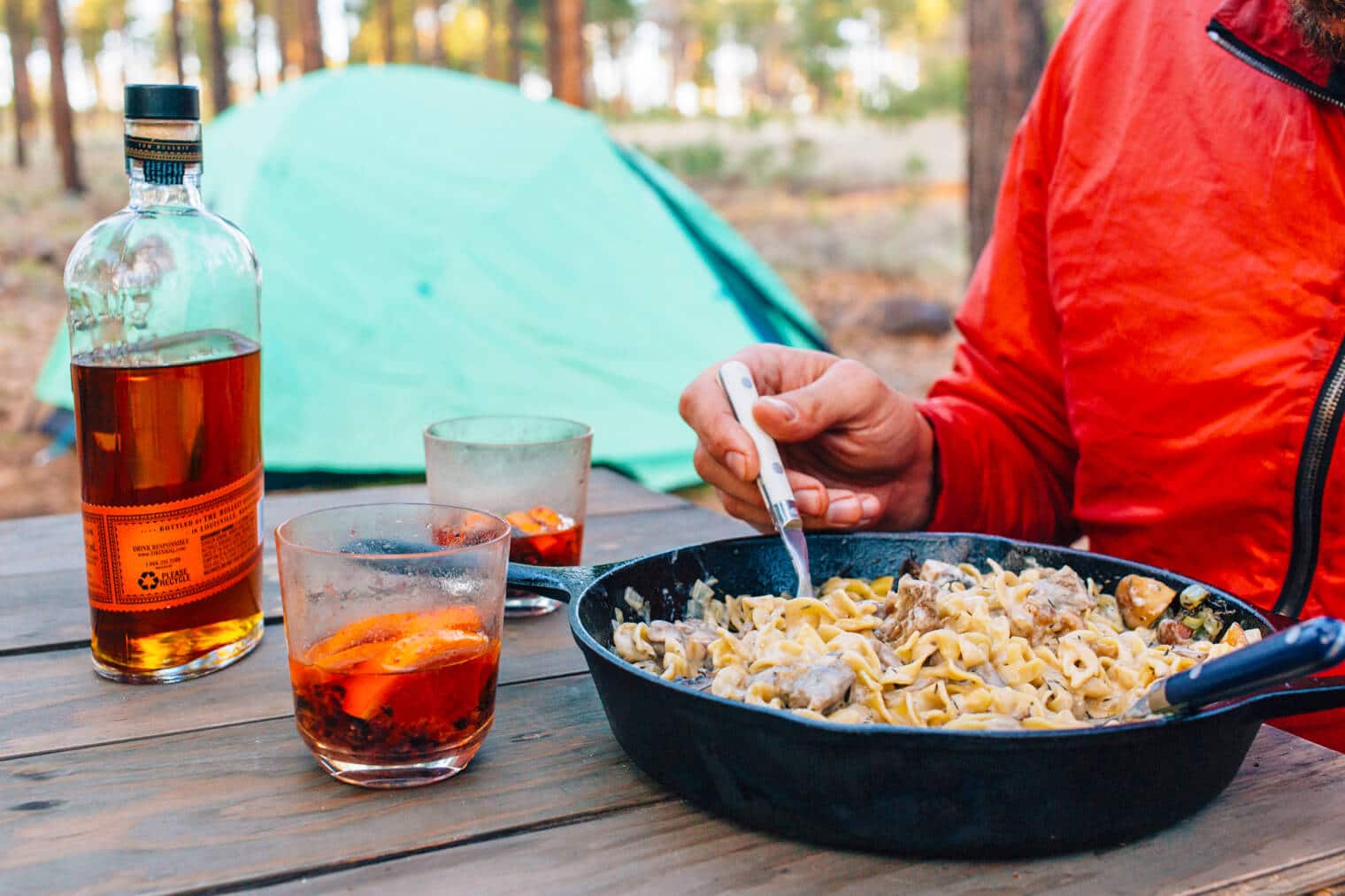 Michael eating beef stroganoff from a cast iron skillet at a campground