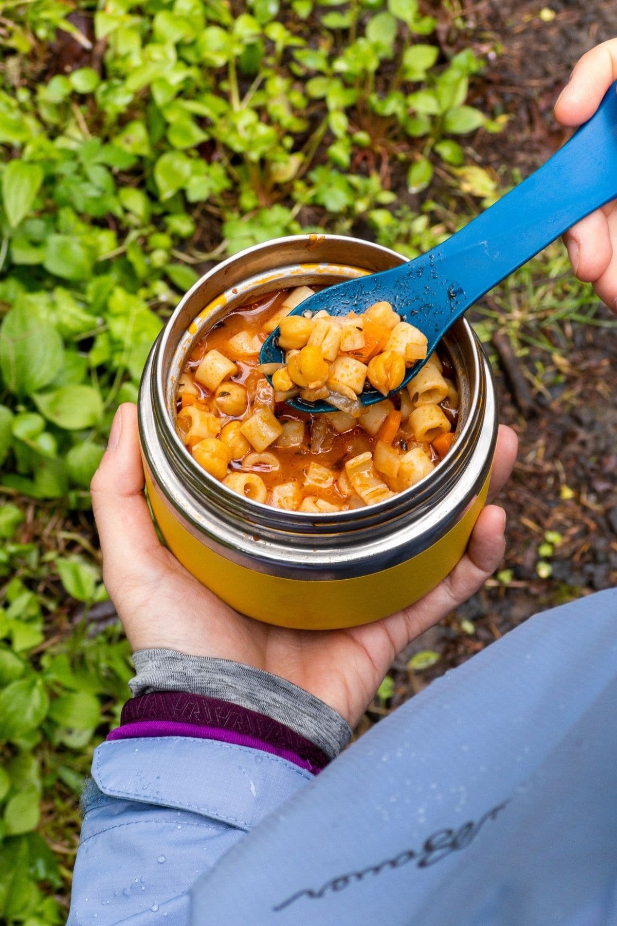 Megan holding pasta e ceci in an insulated container.