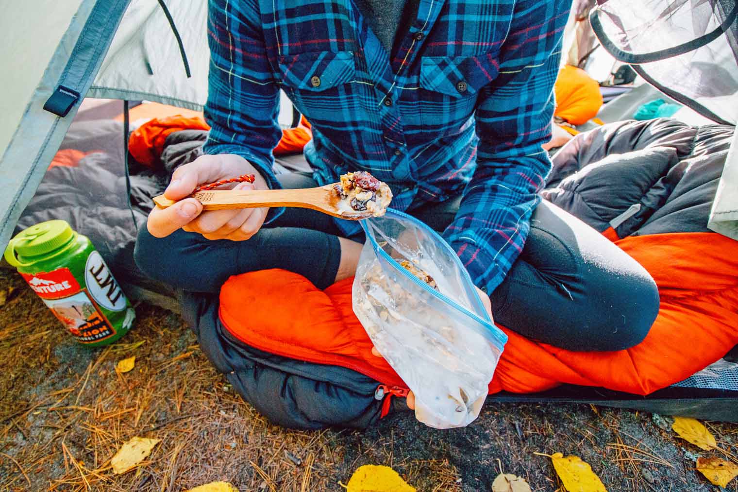 Megan sitting in a tent eating granola from a bag