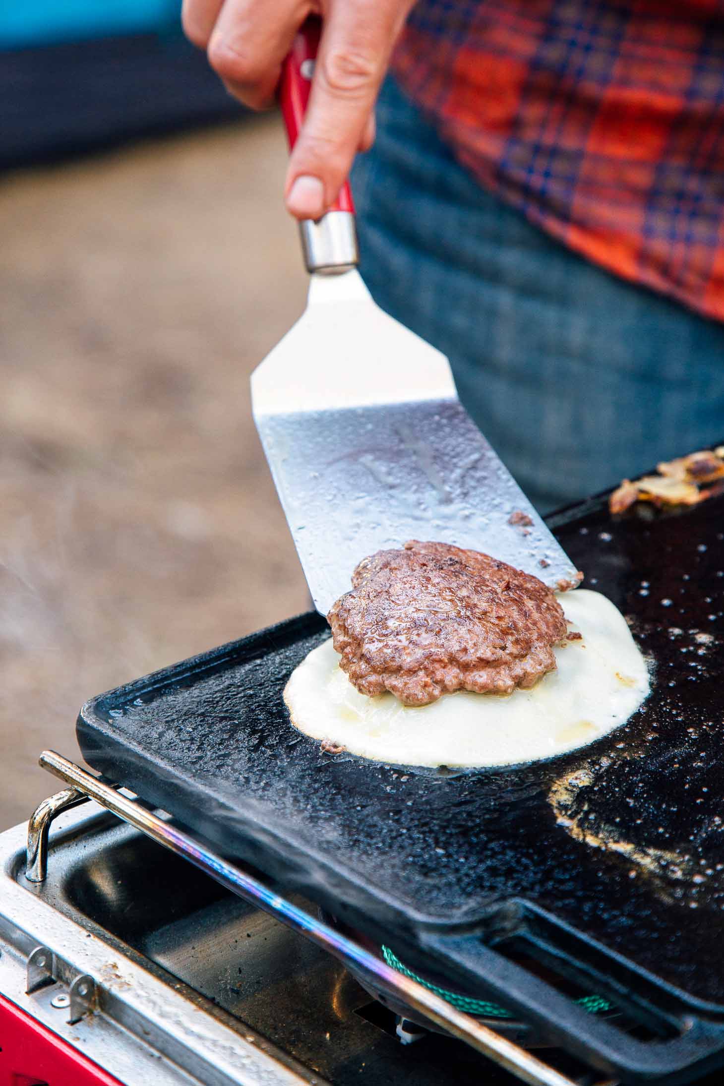 Michael flipping a burger patty on a cast iron griddle