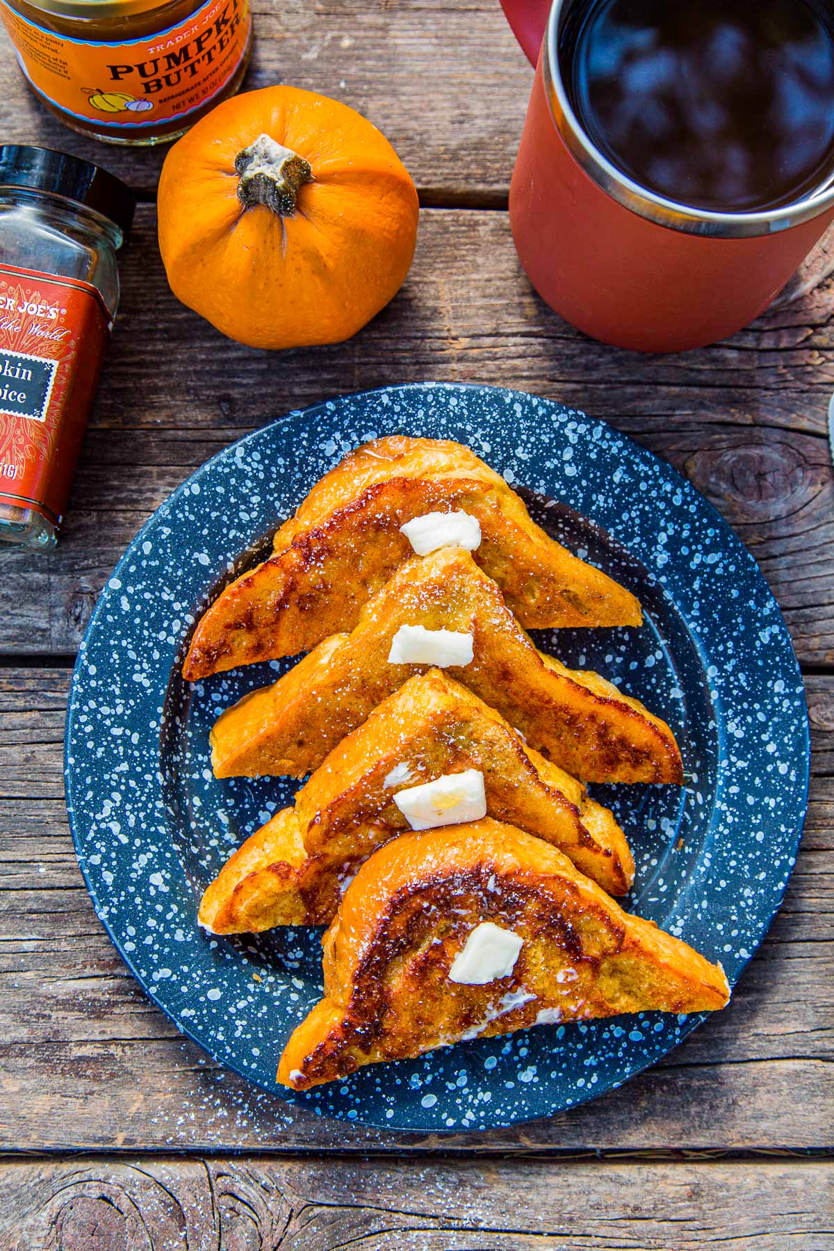 Four slices of pumpkin French toast on a plate next to a cup of coffee