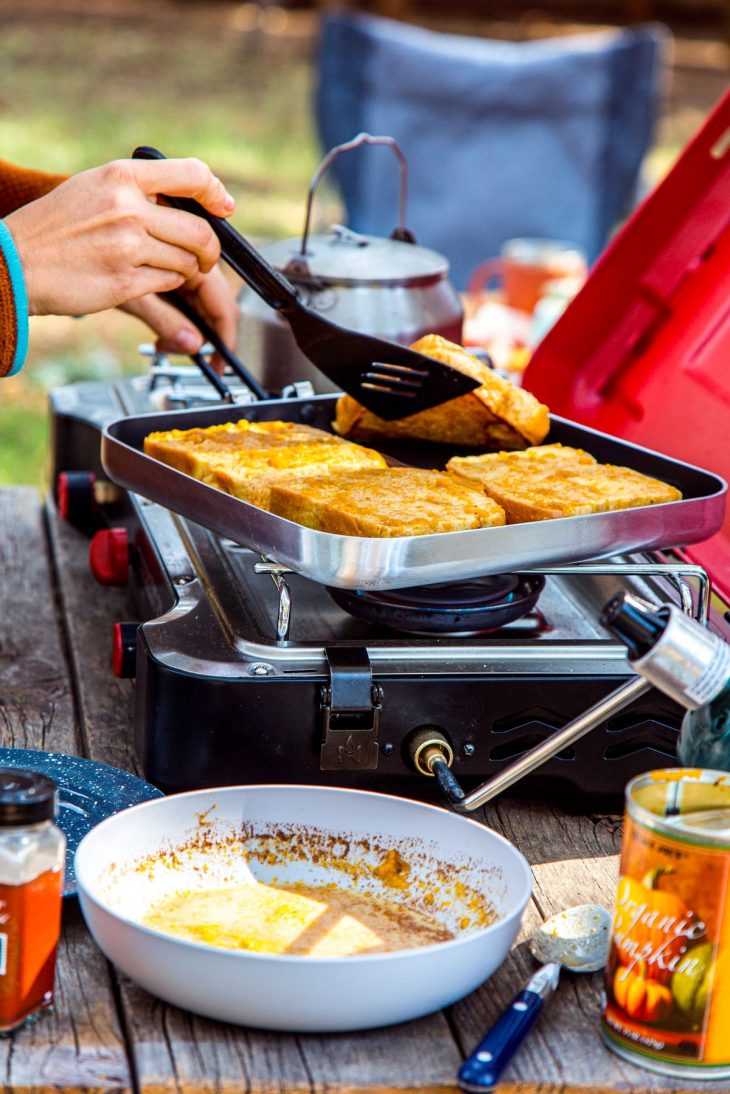 Megan flipping a slice of French toast in a skillet on a camp stove