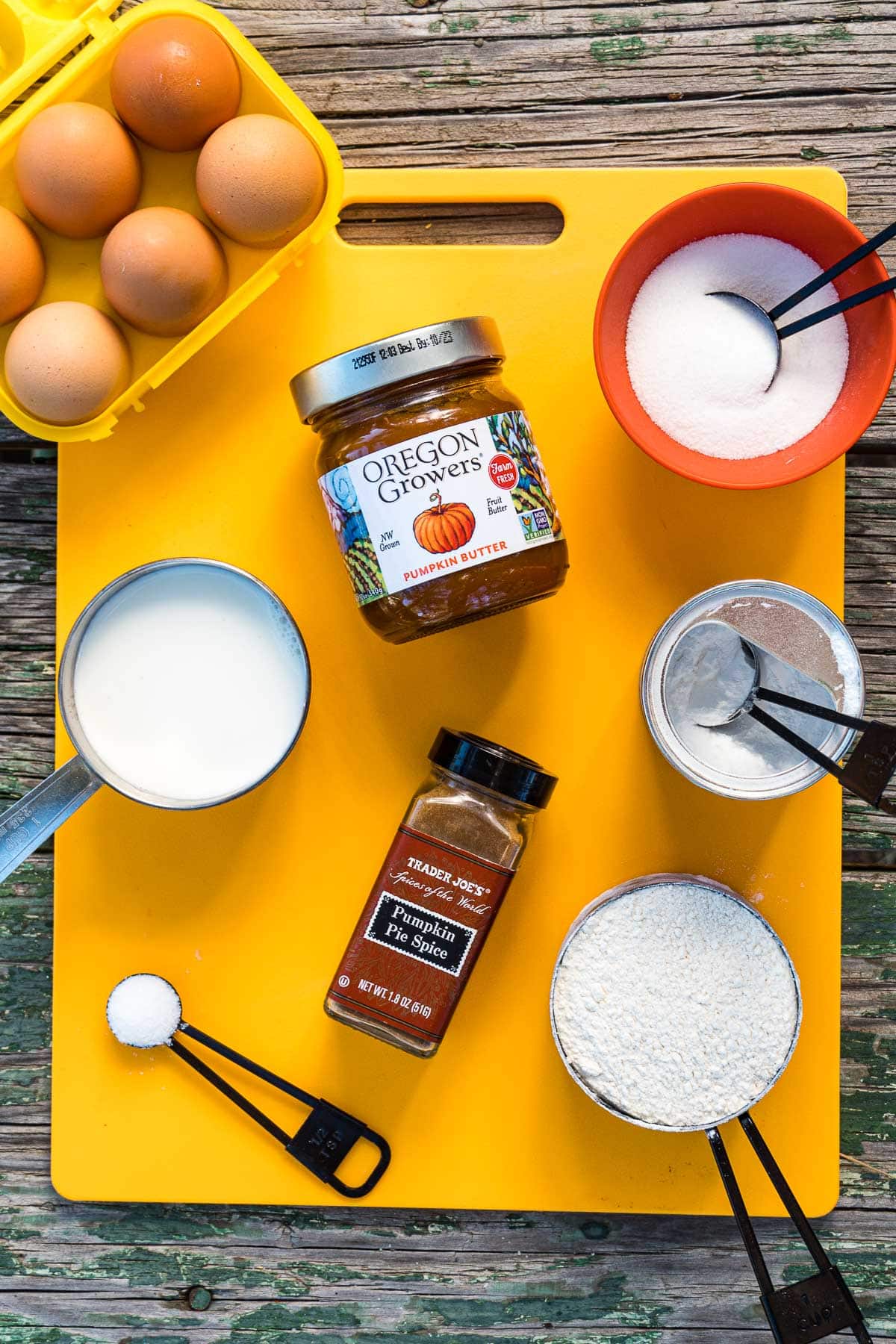 Ingredients to make pumpkin pancakes displayed on a cutting board