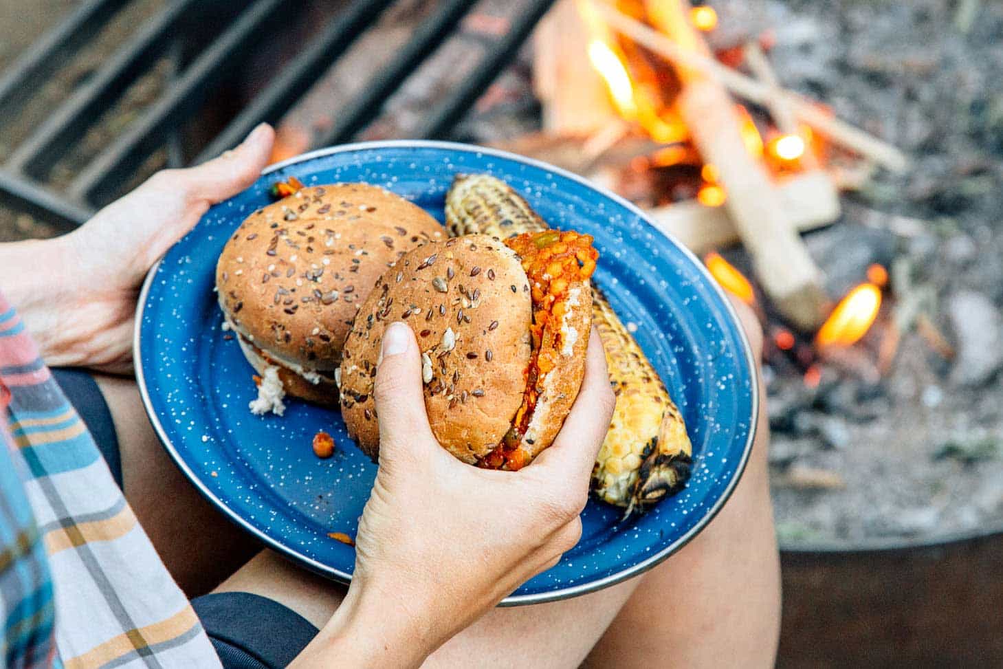 Red lentil sloppy joes on a blue camping plate with a campfire in the background