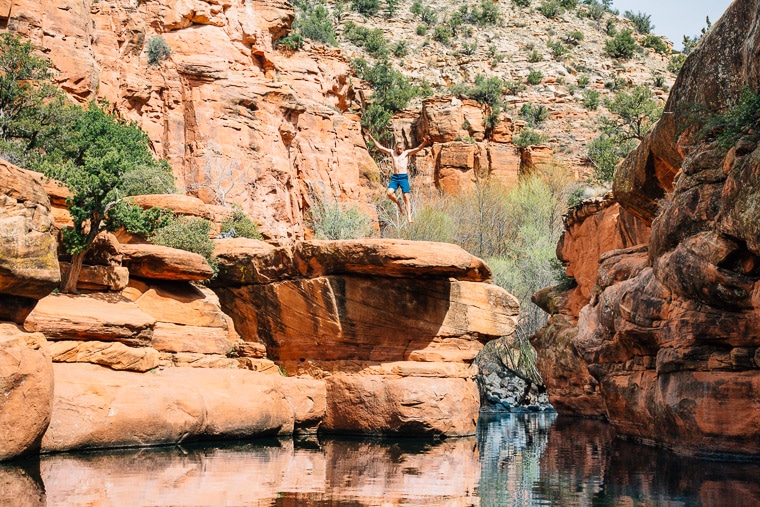 Michael jumping off of a rock into a swimming hole