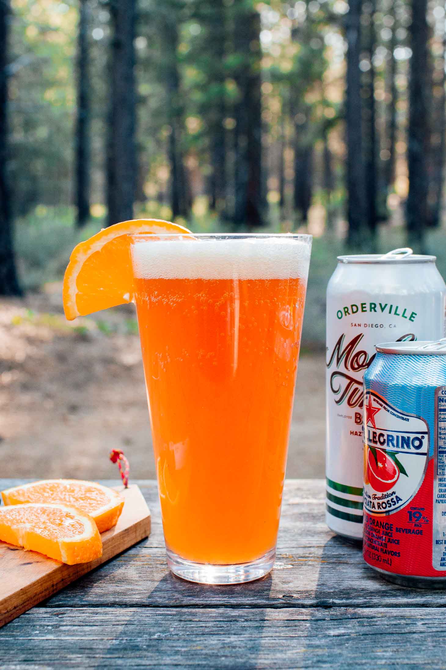 A shandy and ingredients with a forest scene in the background