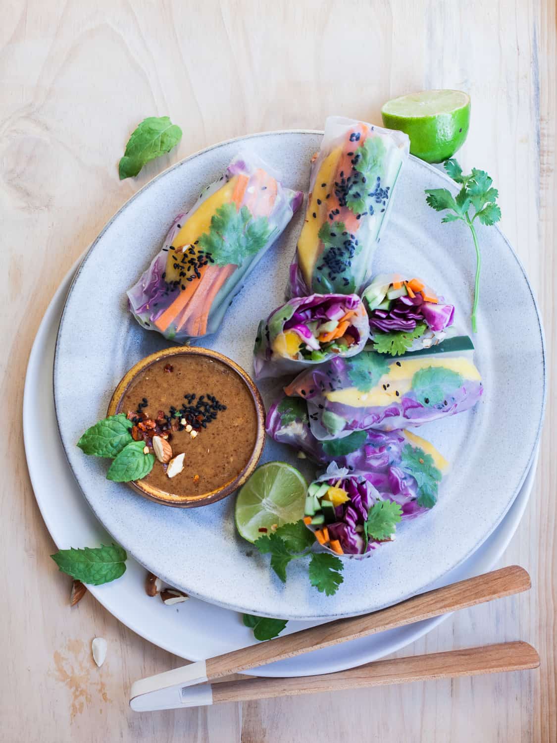 Summer rolls on a white plate with a small bowl of satay