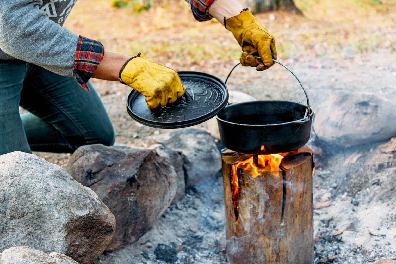 Michael placing a Dutch oven on top of a lit fire log