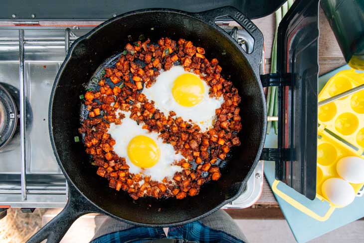 Sunny side up eggs in a camping skillet with sweet potato hash