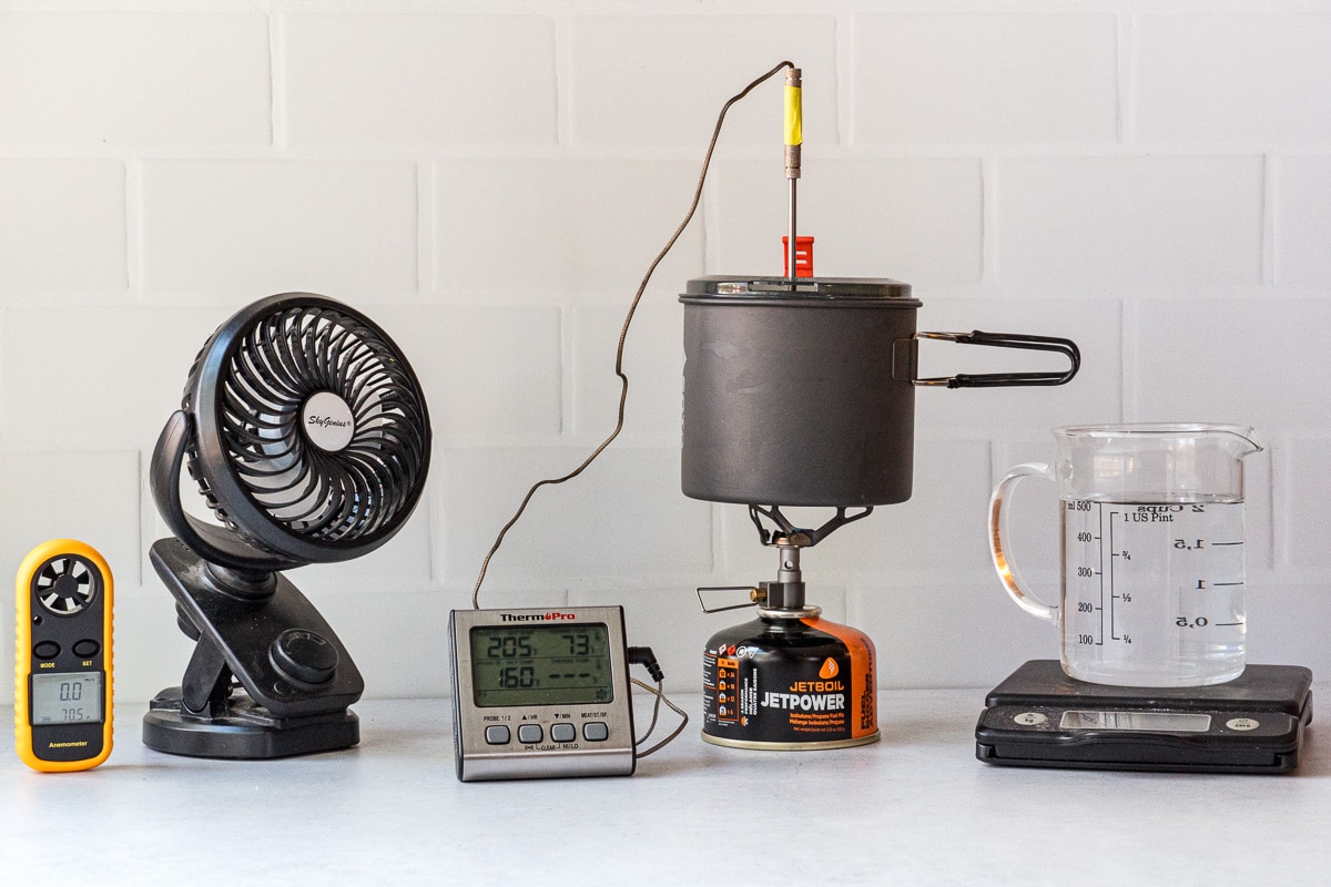 Backpacking stove testing environment including fan, stove and pot, thermometer, scale, and anemometer