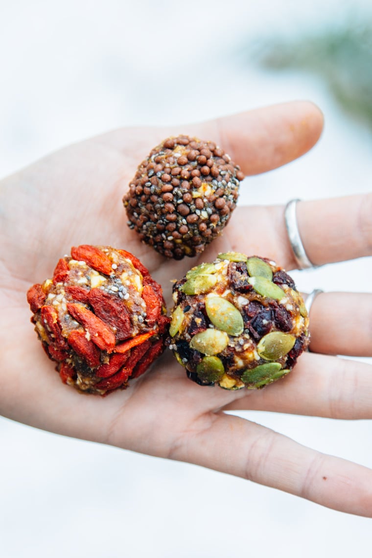 Hand holding three Trail mix bliss balls.