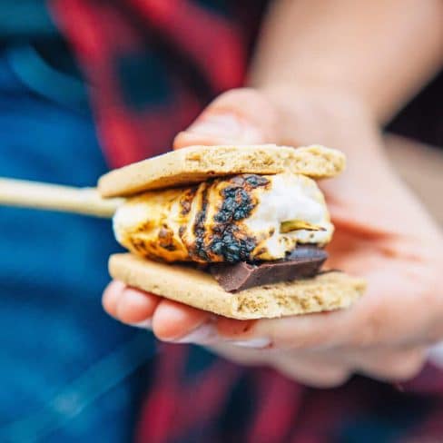 Megan making a s'more with vegan marshmallow, chocolate, and graham crakers