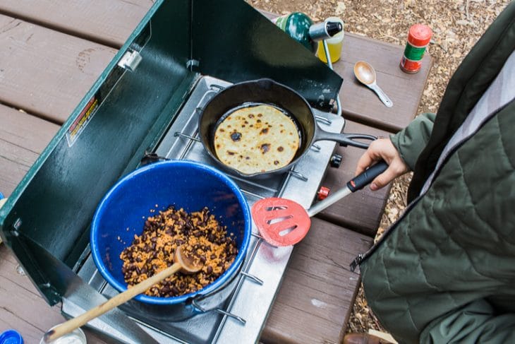 Megan cooking vegan taco filling over a camp stove