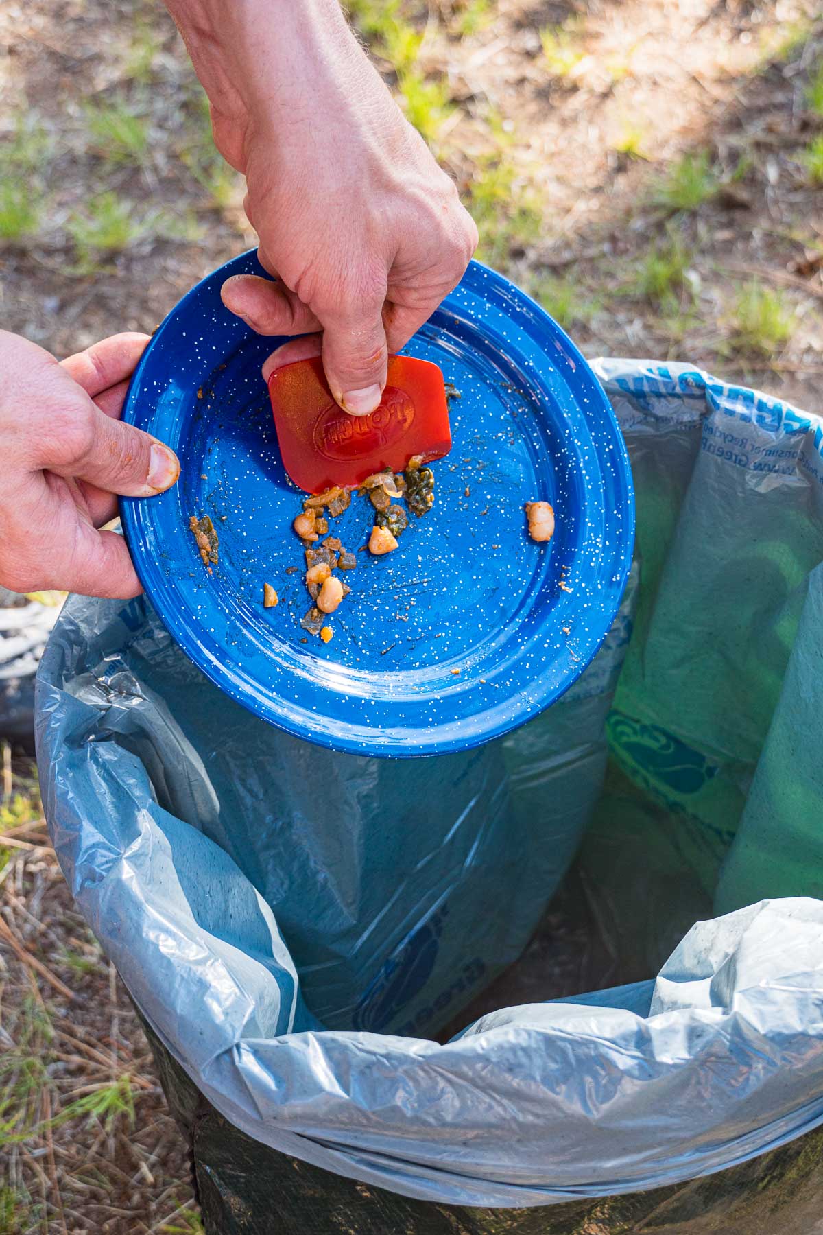 Michael scraping extra food off a plate into the trash