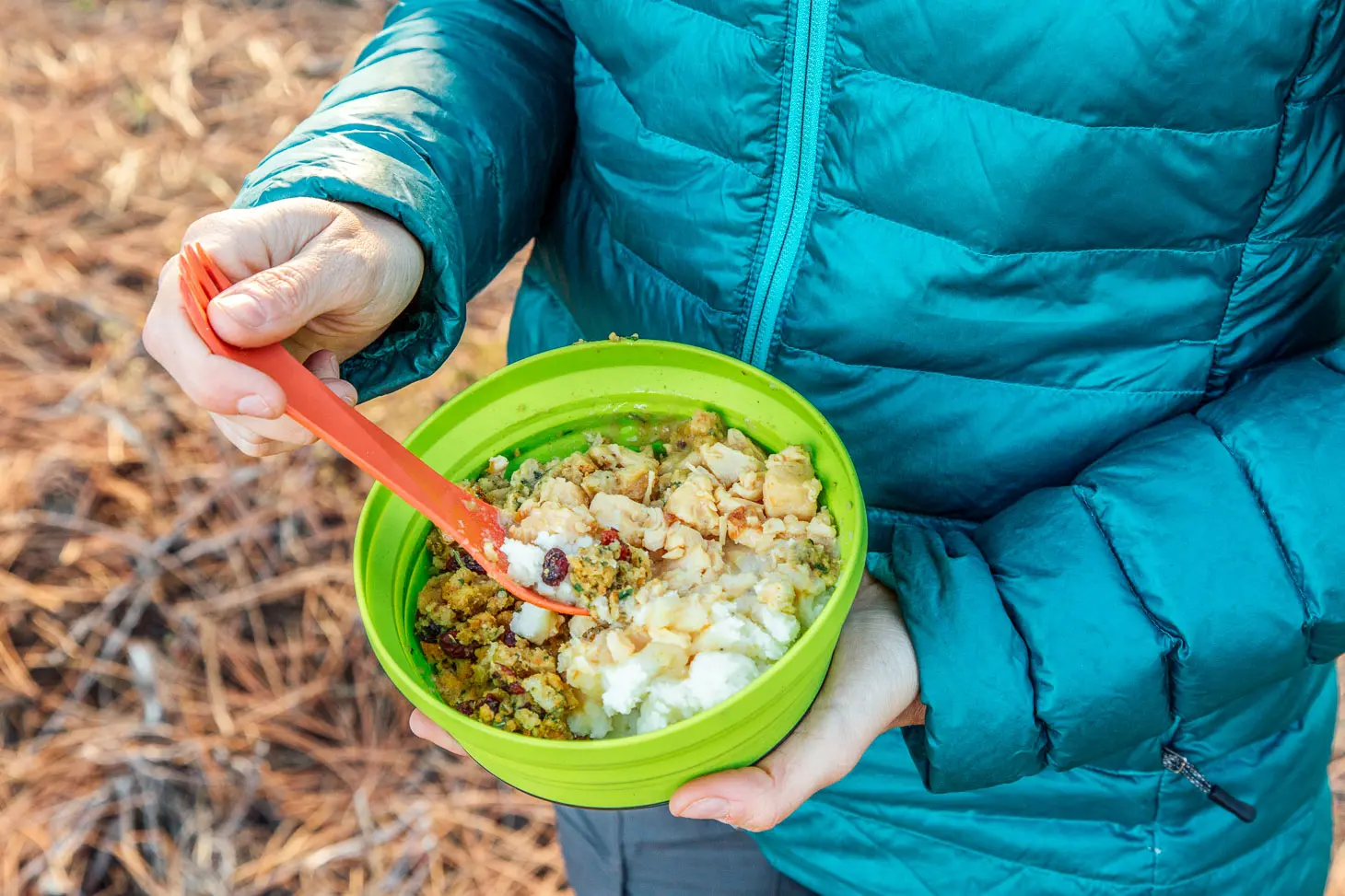 Megan holding a green bowl full of mashed potatoes, stuffing, and chicken and gravy.