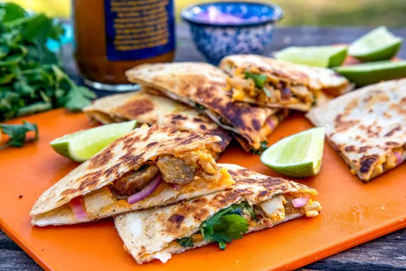 Sliced quesadillas stacked on an orange cutting board.