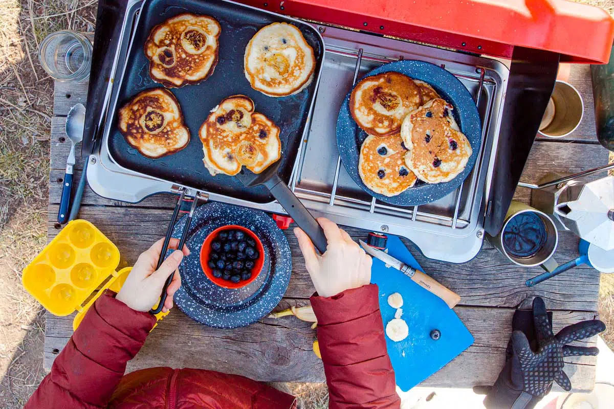 Megan making pancakes on a griddle over a camping stove