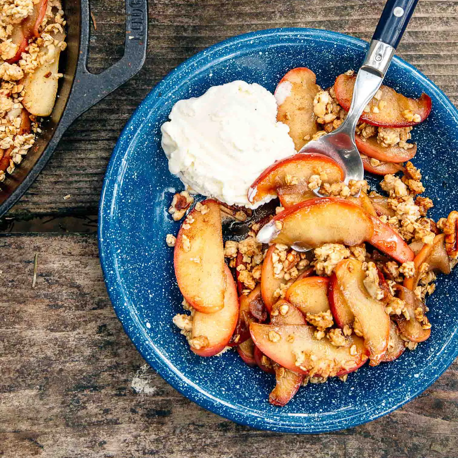 Apple crisp with whipped cream in a blue bowl