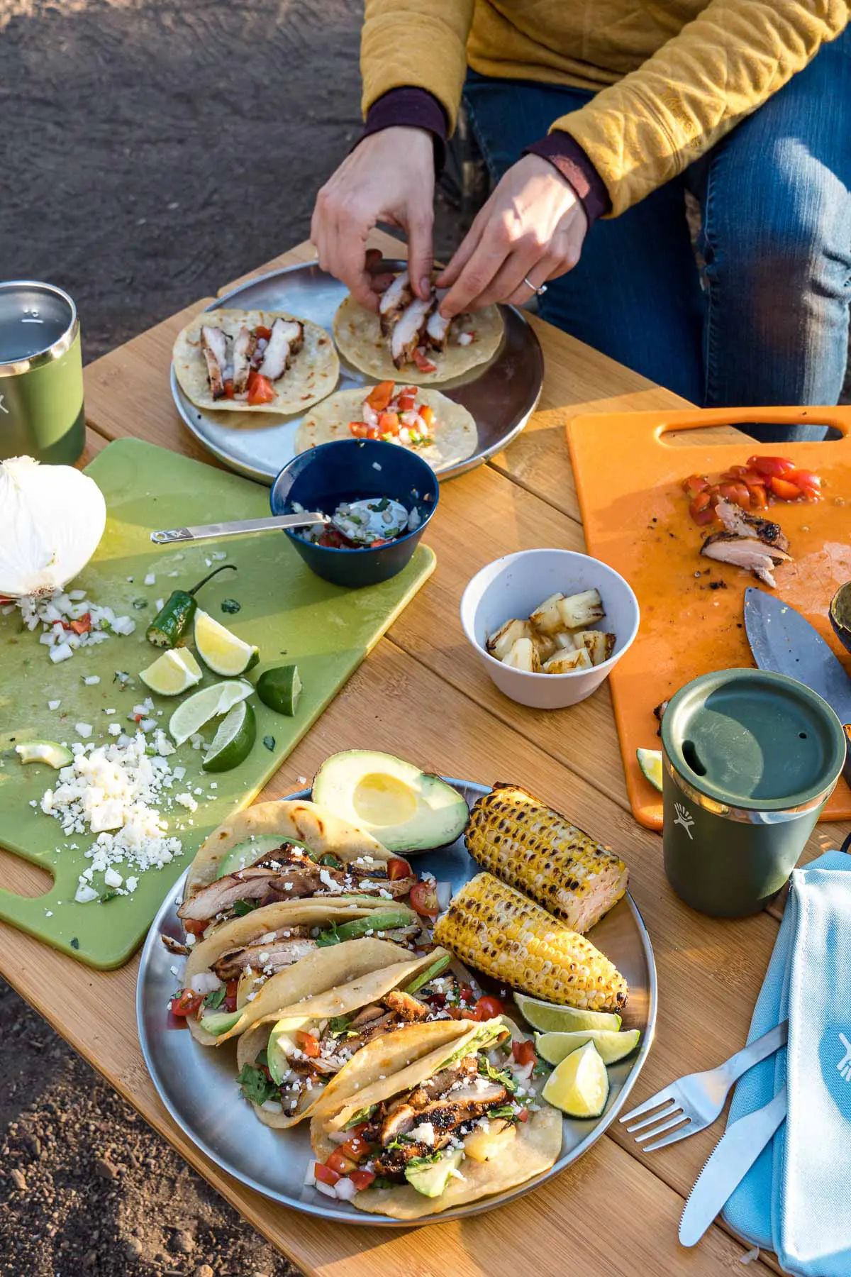 A table scene with a plate of tacos in the foreground and Megan's hands assembling tacos on a second plate