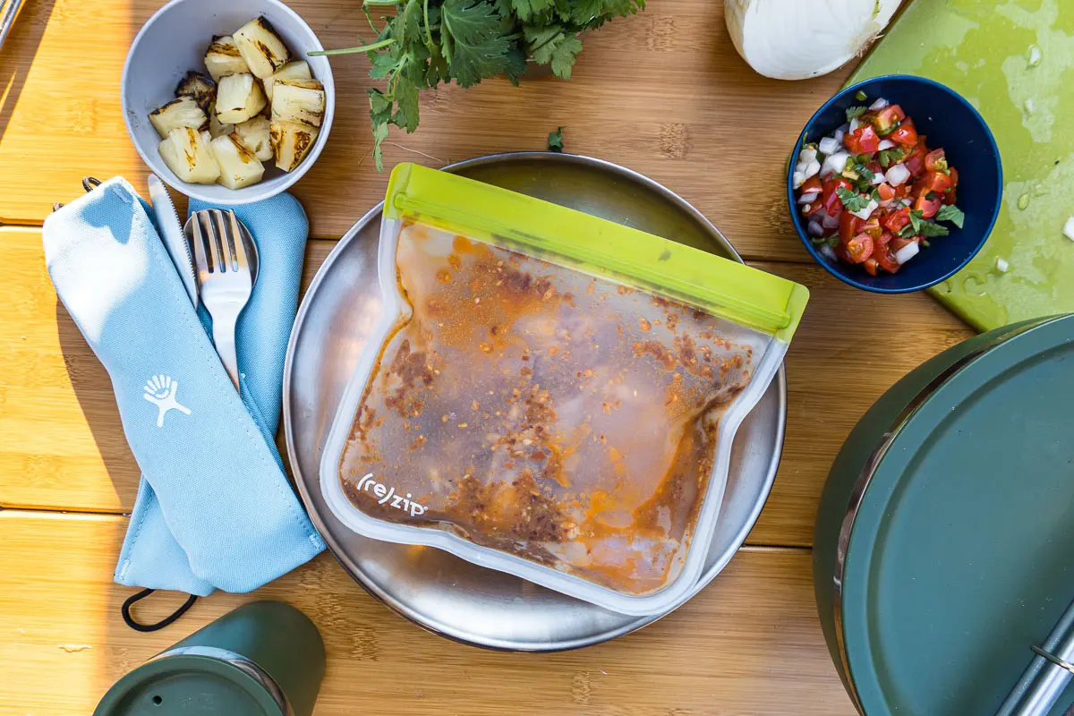 A ziplock bag containing chicken in marinade resting on a plate