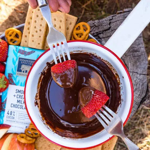 Two forks dipping strawberries into a bowl of chocolate fondue