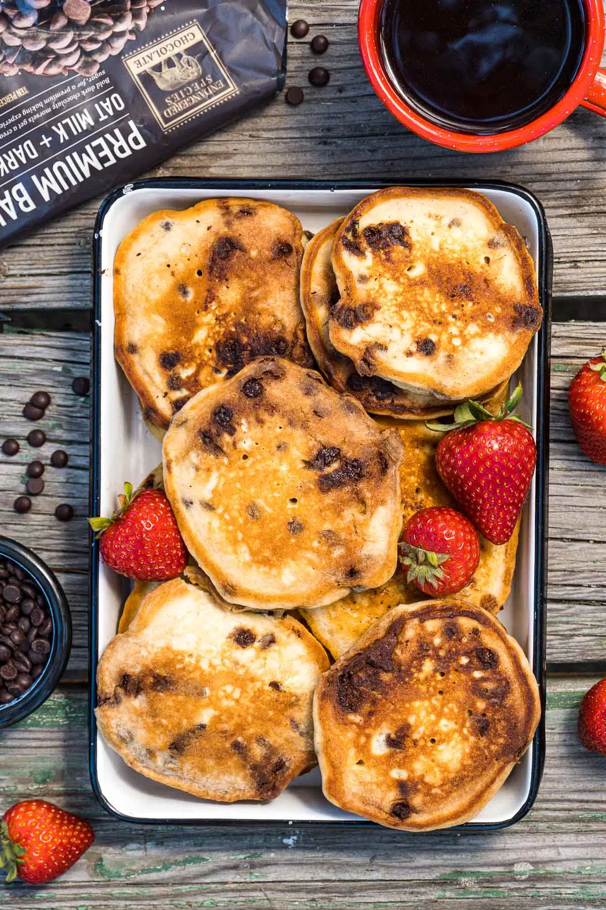 A platter of chocolate chip pancakes on a wooden table