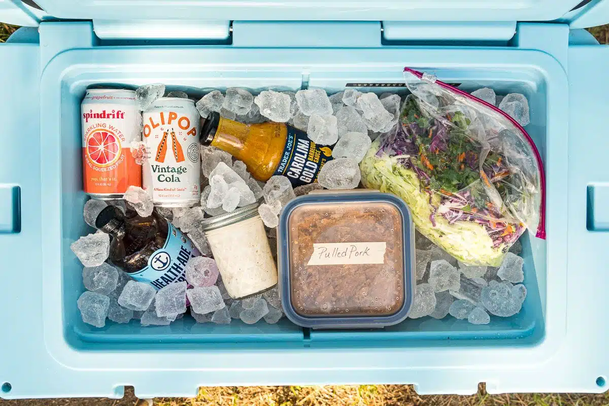 A cooler filled with ice, coleslaw components, and other items.