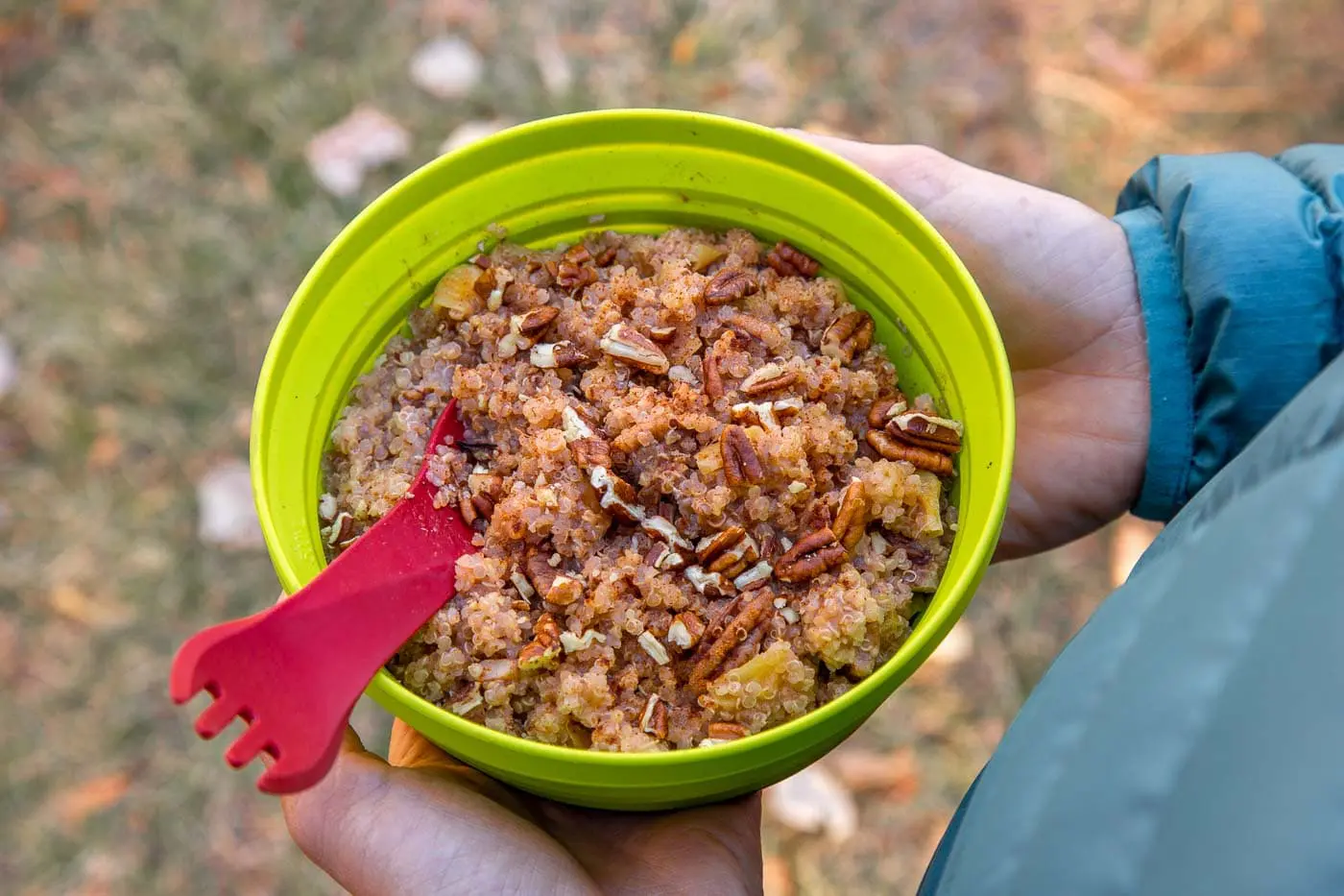 Overhead view of Megan holding a green backpacking bowl full of apple quinoa porridge