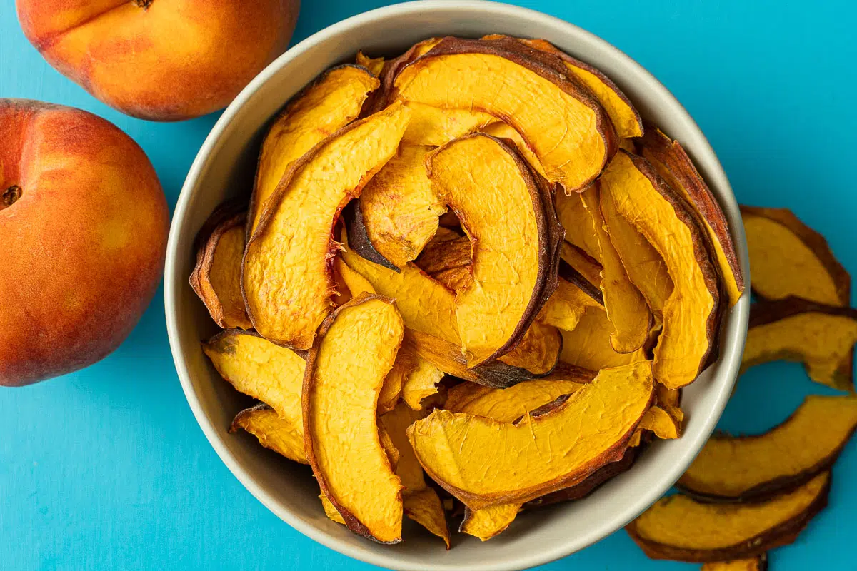 Dehydrated peaches in a bowl with a blue background