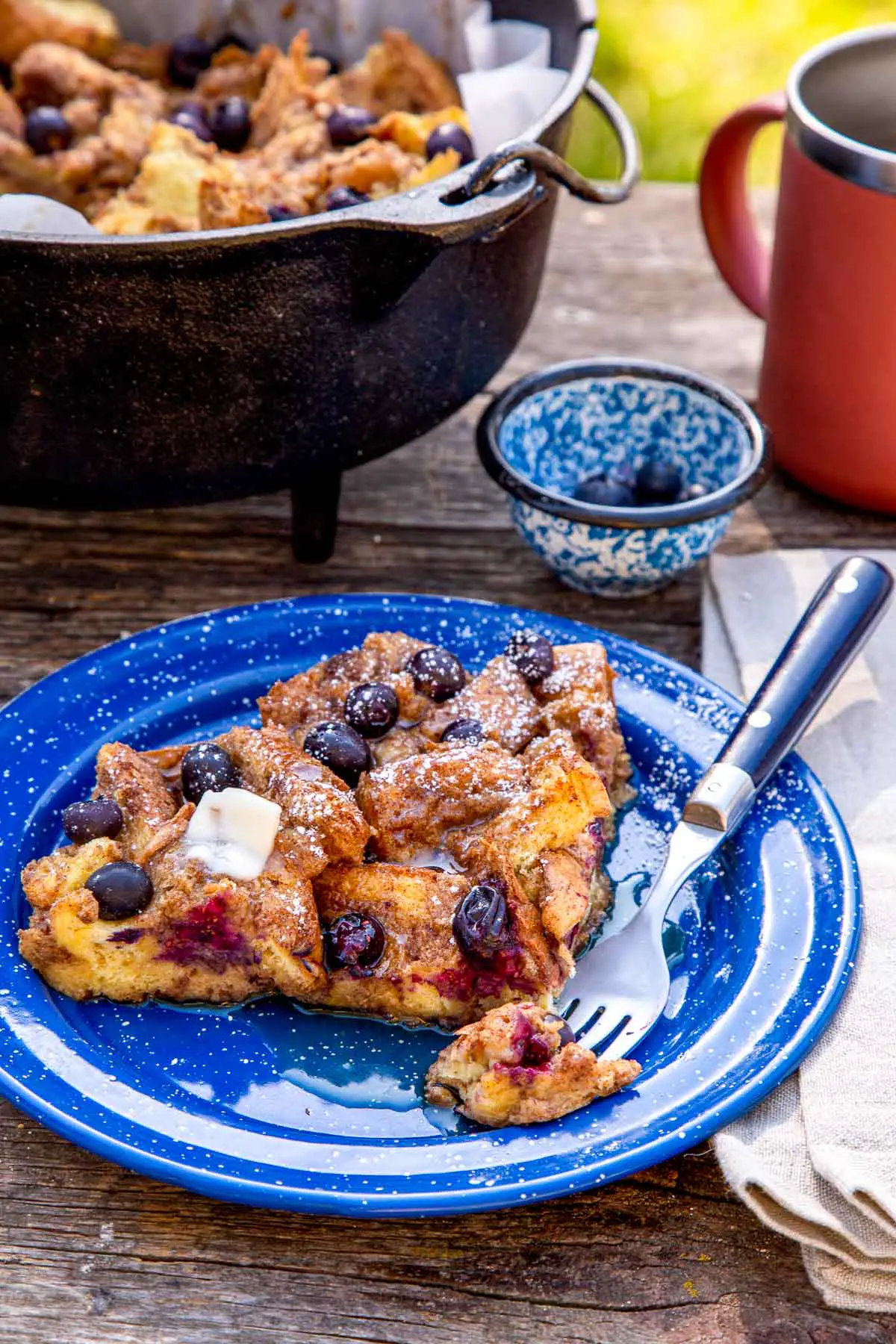 A slice of baked French toast on a blue plate. A fork is on the side with a bite sized piece of toast.