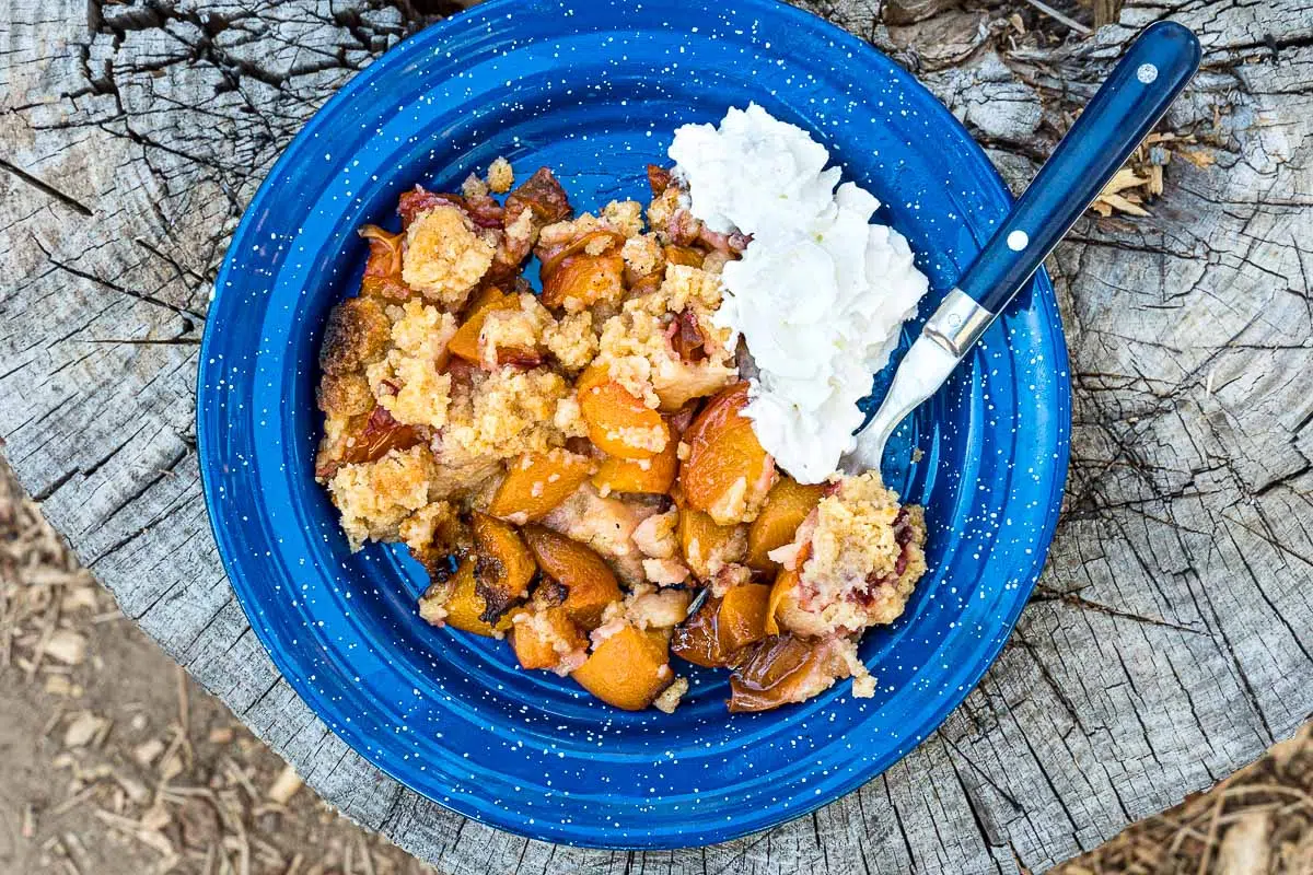 Peach cobbler and whipped cream on a blue plate