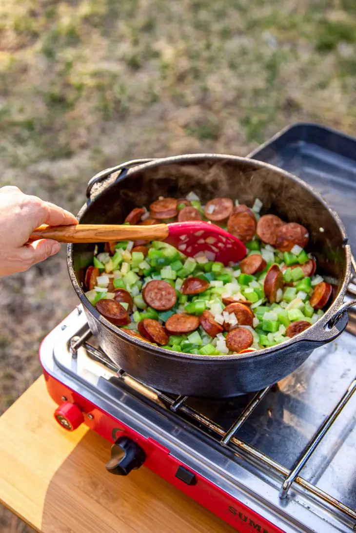 Megan stirring vegetables and sausage in a Dutch oven.