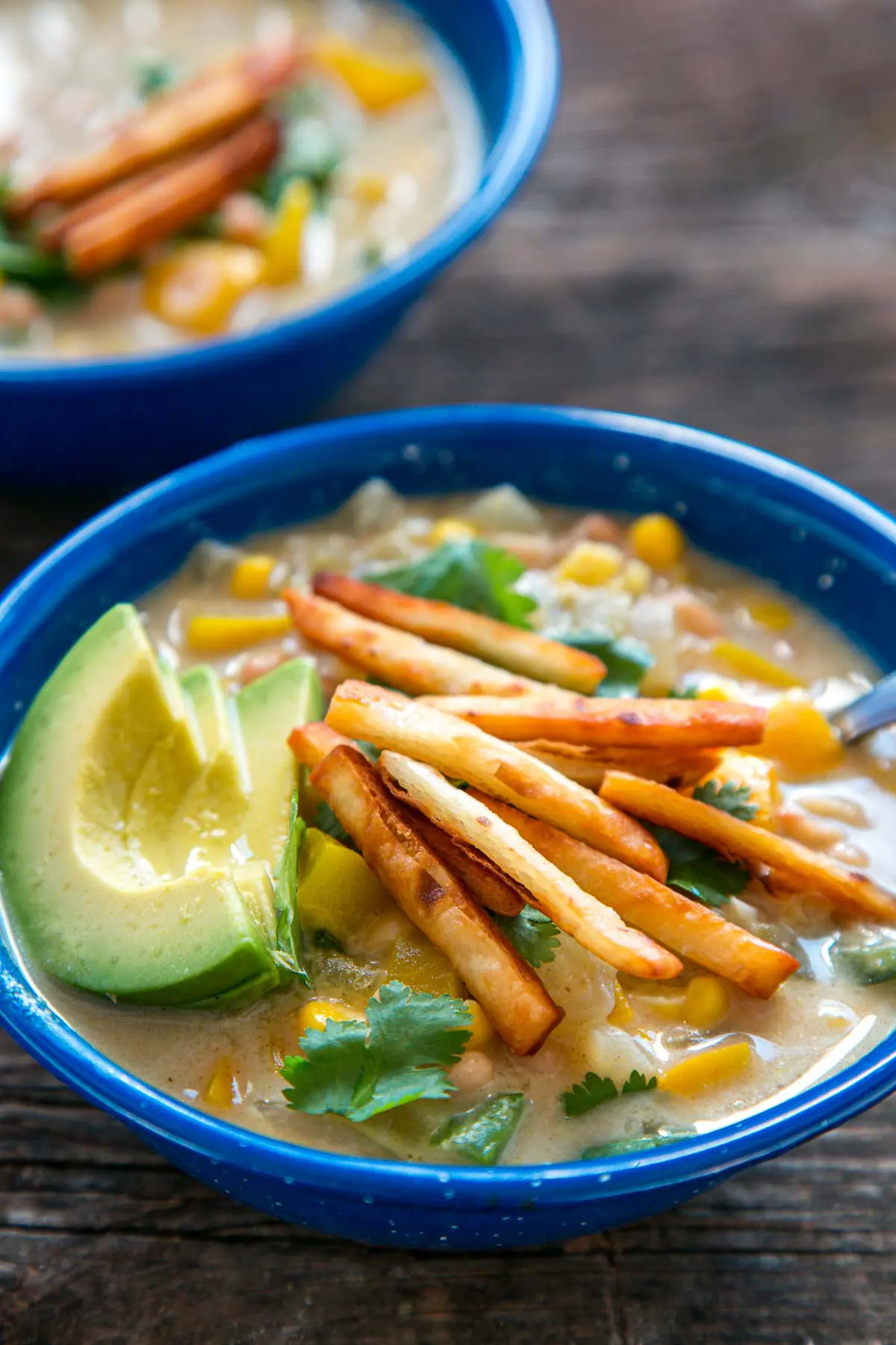 Two blue bowls of white bean chili on a table