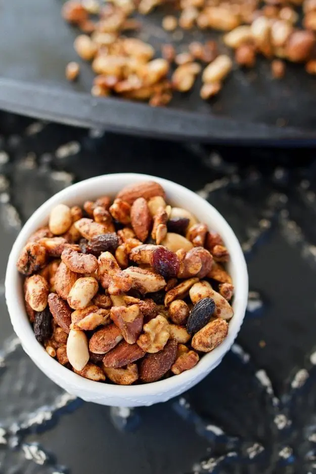 Trail mix in a white bowl on a dark surface