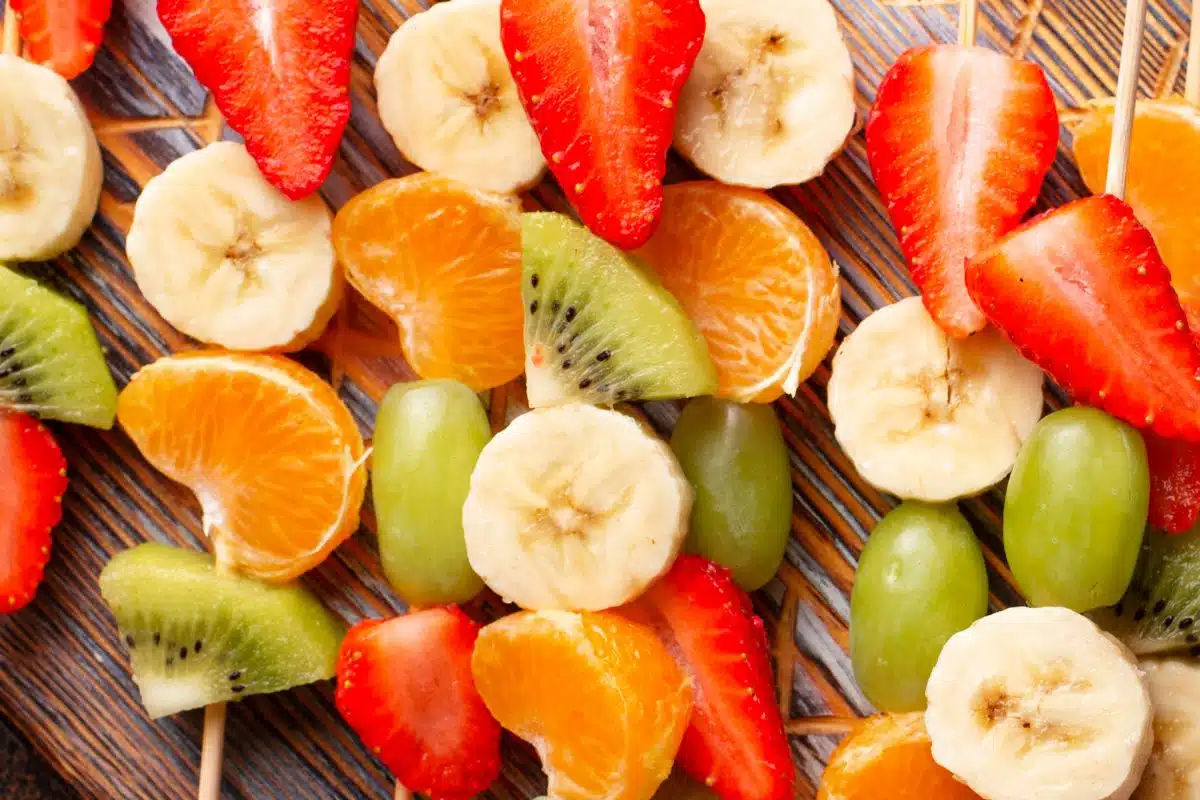 Cut banana, kiwi, strawberries, and oranges.