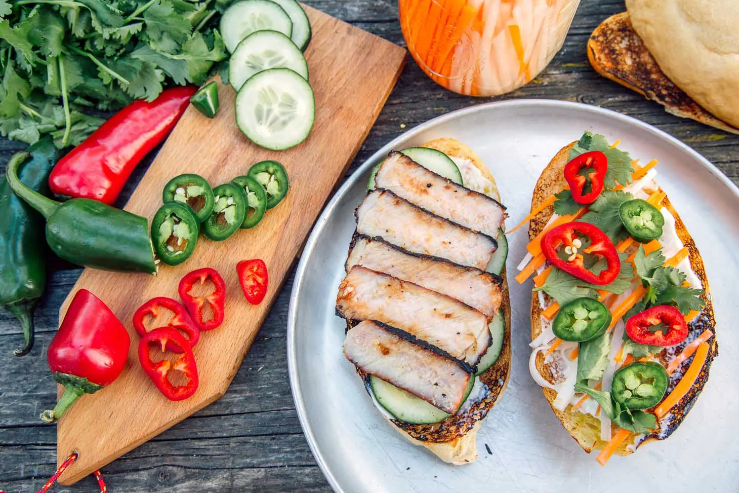 A banh mi sandwich open faced on a silver camping plate