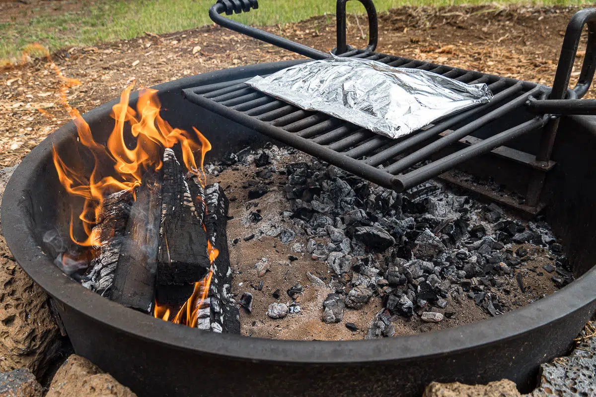 Foil packet on a campfire grill over a bed of embers