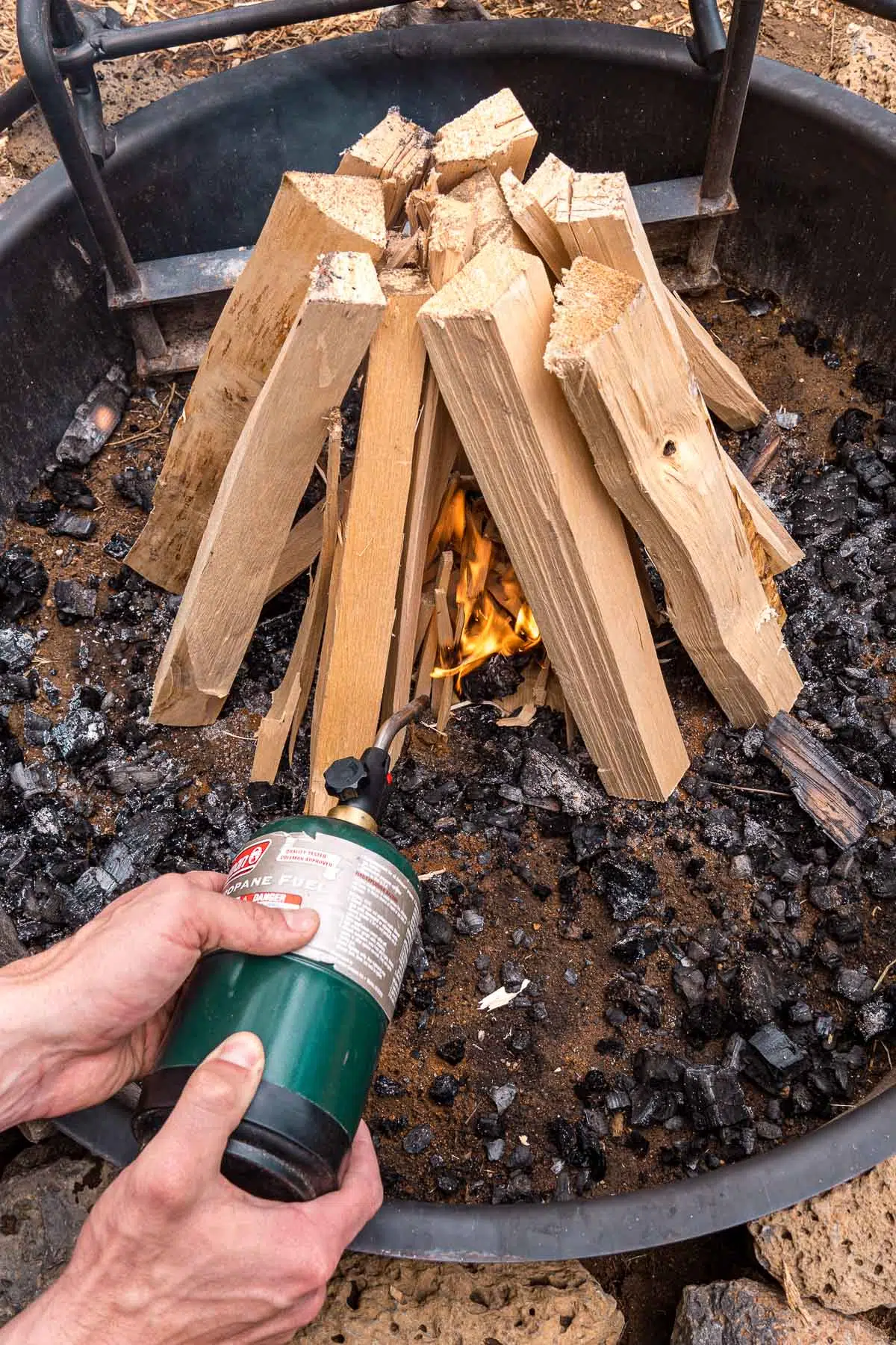 Michael using a camp torch to light a campfire