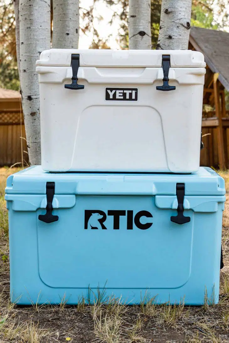 A white cooler stacked on top of a larger blue cooler