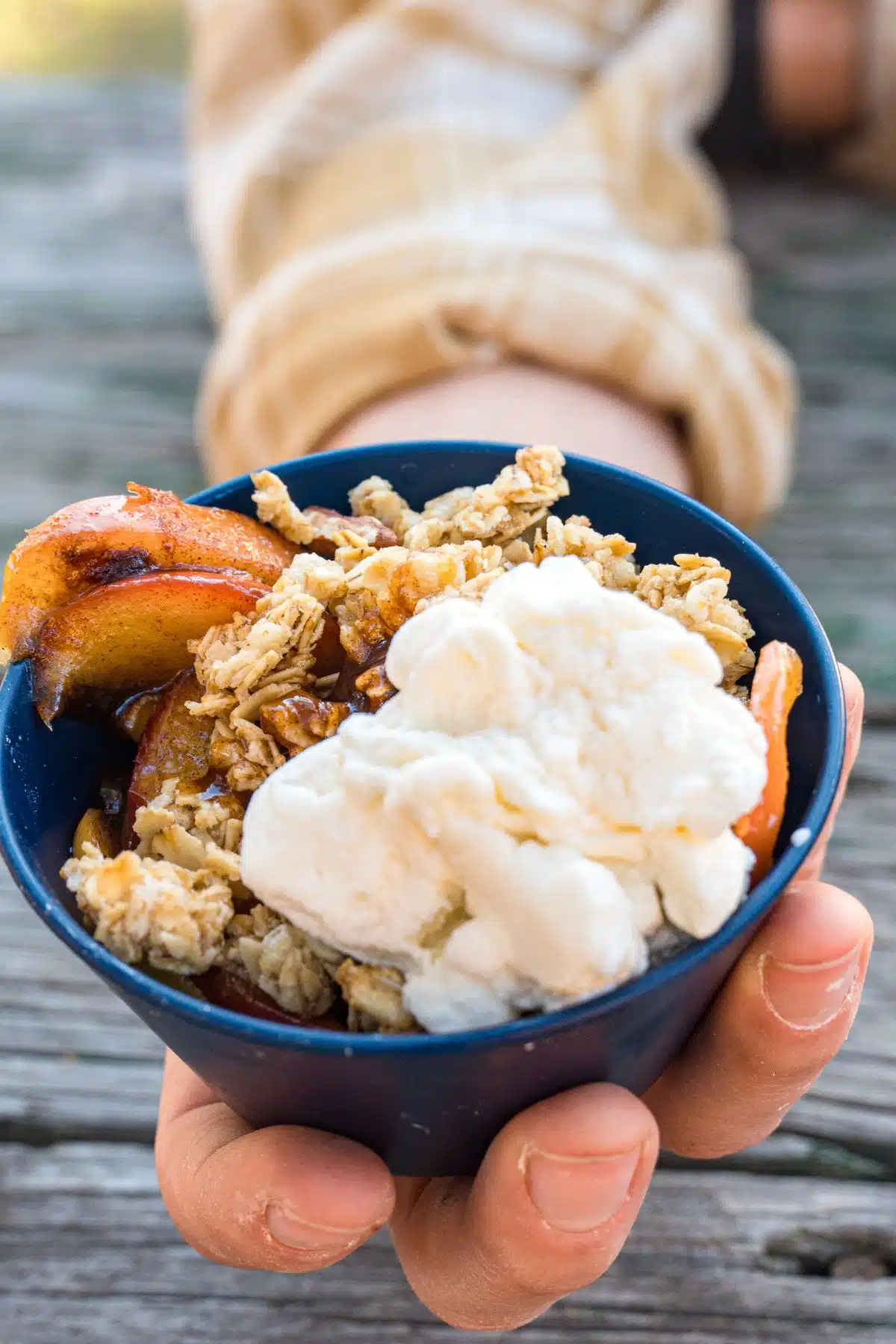 A hand holding a small bowl of ice cream.