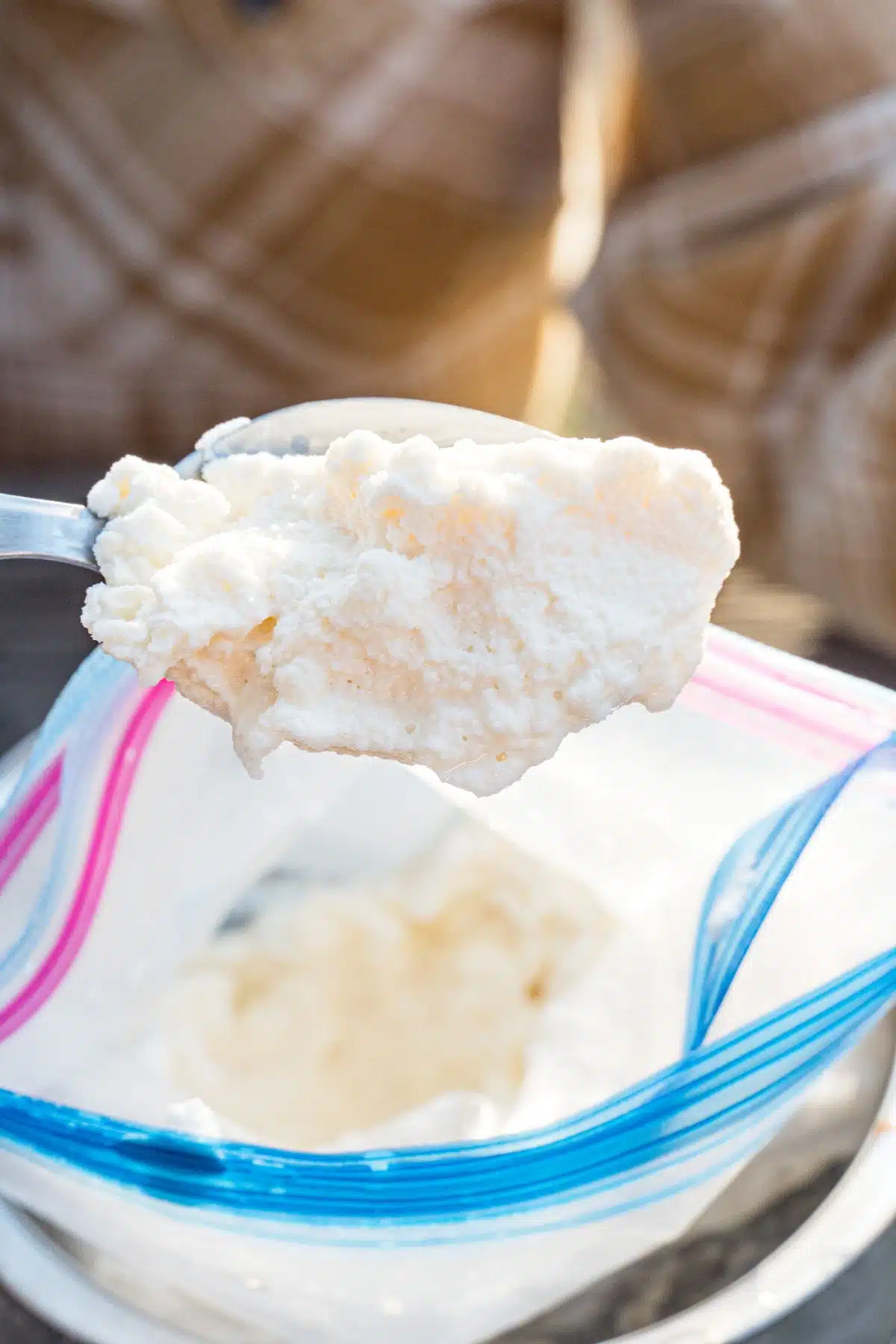 Using a spoon to scoop ice cream from a bag.