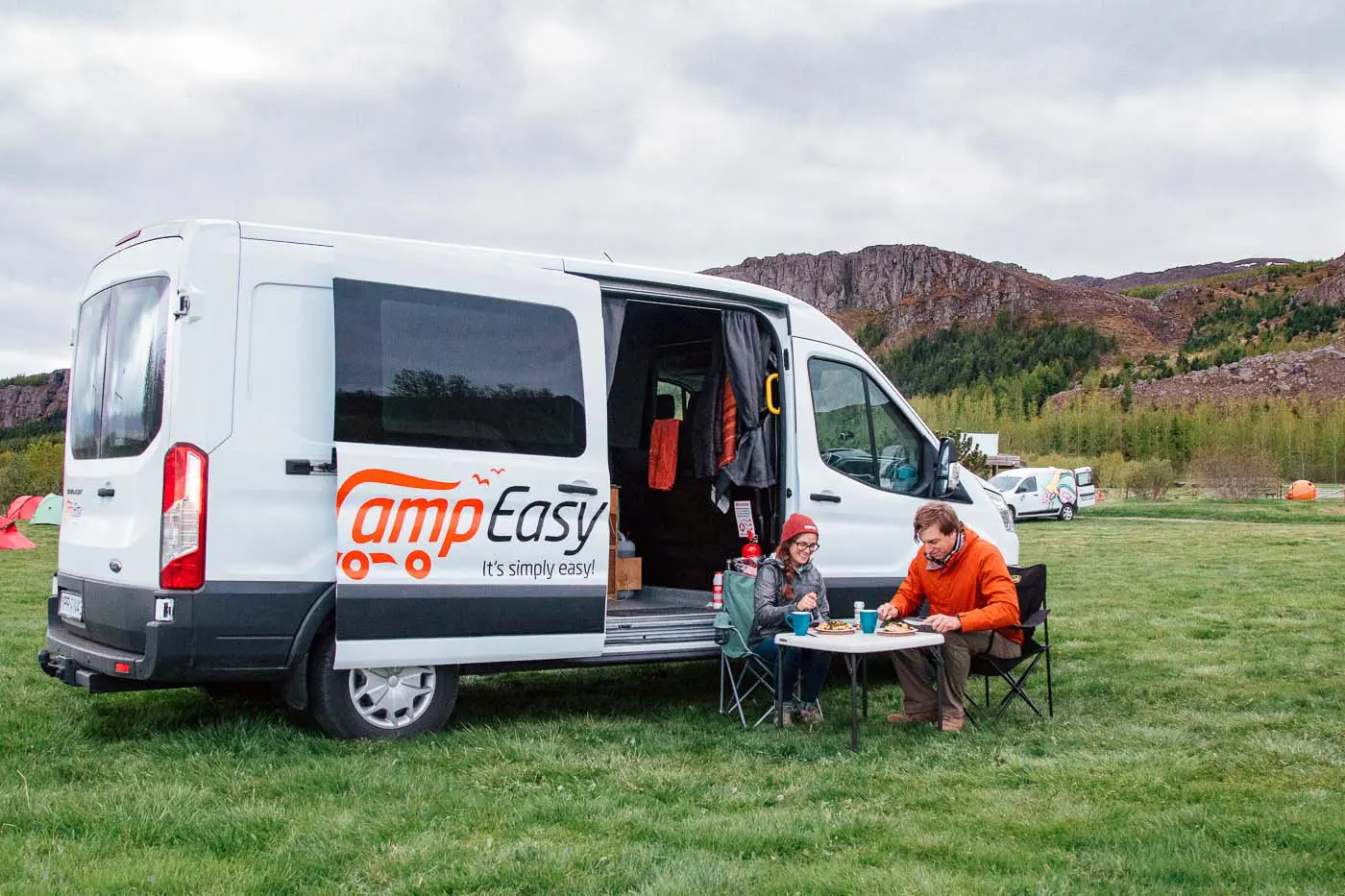 A couple eating a meal in front of a camper van