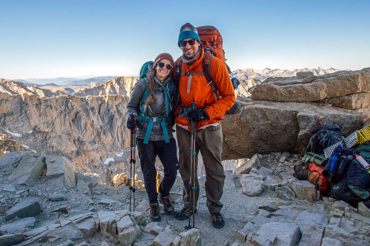 Megan and Michael wearing their backpacking gear with mountains in the distance