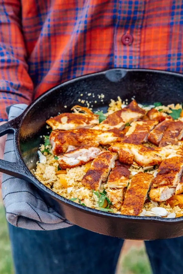 Michael holding a skillet of Moroccan spiced chicken with couscous